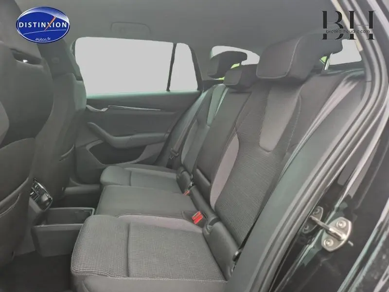 Vue latérale intérieure sur la banquette arrière noire du Skoda Octavia Combi 2024 avec sièges en tissu gris et noir.