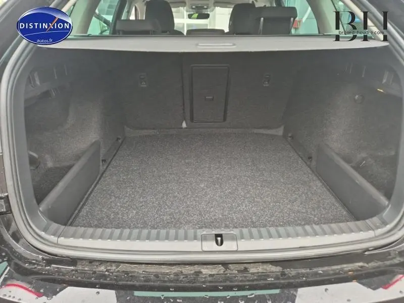 Coffre ouvert vu de l'arrière d'une Skoda Octavia Combi noir Magic nacré, espace de chargement vide et tapis gris.