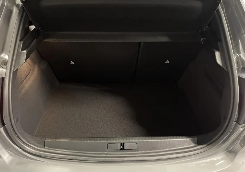Coffre ouvert vu de face, intérieur noir, carrosserie gris selenium métallisée visible autour de l'ouverture.