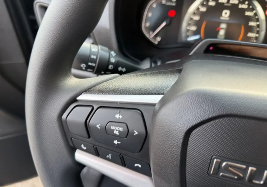 Gros plan sur le volant multifonctions noir du pick-up Isuzu D-MAX 2026 avec commandes audio et téléphone intégrées.