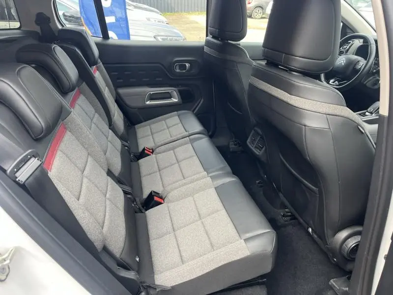 Vue intérieure côté droit des sièges arrière gris et noirs du Citroën C5 Aircross Blanc Banquise avec détails rouges et volant visible à l'avant.