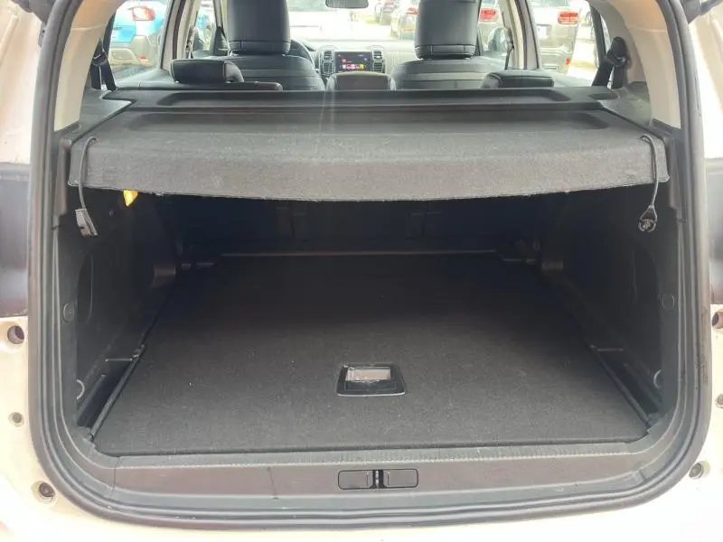 Coffre ouvert vu de l'arrière d'un Citroën C5 Aircross blanc Banquise, avec cache-bagages en place et sièges arrière visibles.