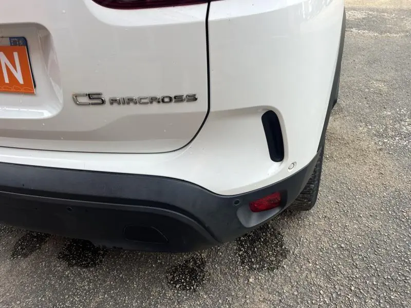 Gros plan sur l'arrière droit blanc Banquise d'un Citroën C5 Aircross avec logo et feu antibrouillard intégré.