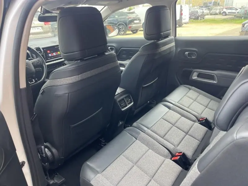 Intérieur arrière du Citroën C5 Aircross blanc, vue côté gauche montrant les sièges individuels en tissu gris et cuir noir.