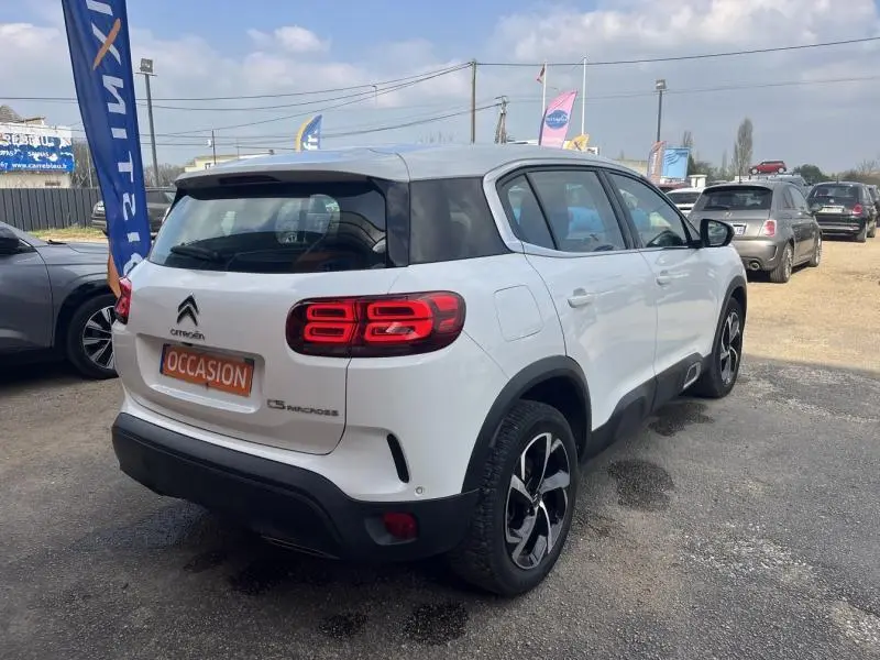 Vue 3/4 arrière droite d'un Citroën C5 Aircross blanc Banquise avec feux arrière LED et jantes alliage noires.