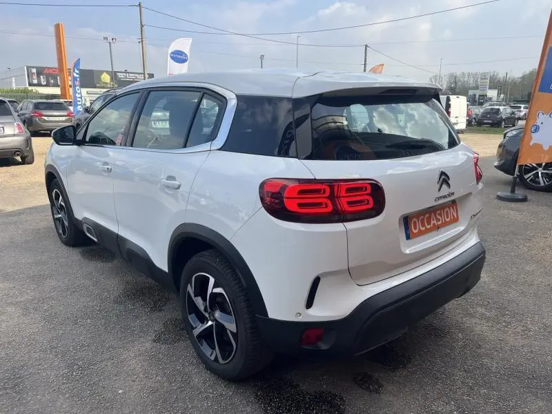 Vue 3/4 arrière droite d'un Citroën C5 Aircross blanc Banquise avec feux arrière LED et jantes alliage noires.