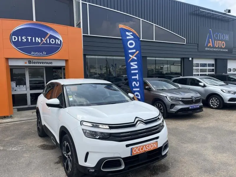 Citroën C5 Aircross blanc banquise en 3/4 avant droit, avec jantes alu et calandre distinctive, devant un concessionnaire.