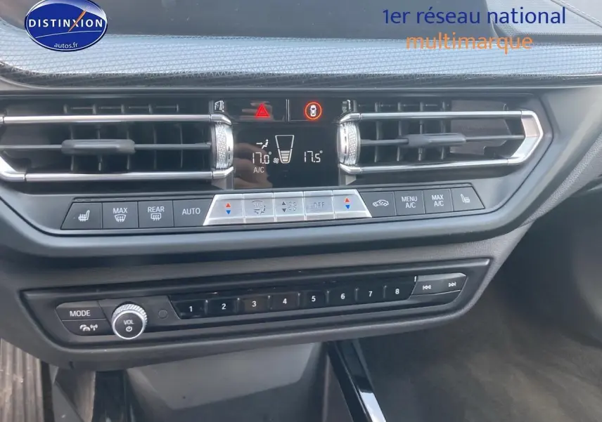 Vue rapprochée du tableau de bord de la BMW Série 1 gris foncé, mettant en valeur les commandes de climatisation et audio.