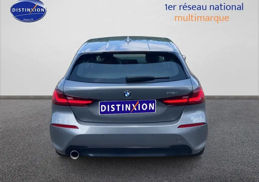 Vue arrière d'une BMW Série 1 118i gris foncé avec feux LED et sortie d'échappement visible à gauche.