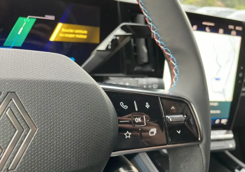 Vue rapprochée du volant du Renault Austral New 200 Esprit Alpine bleu outremer, avec commandes multifonctions et coutures tricolores.