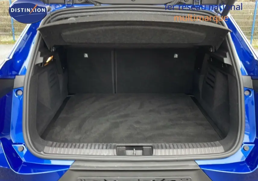 Coffre ouvert vu de l'arrière d'une Renault Symbioz bleu iron metal, montrant un espace de chargement spacieux et propre.