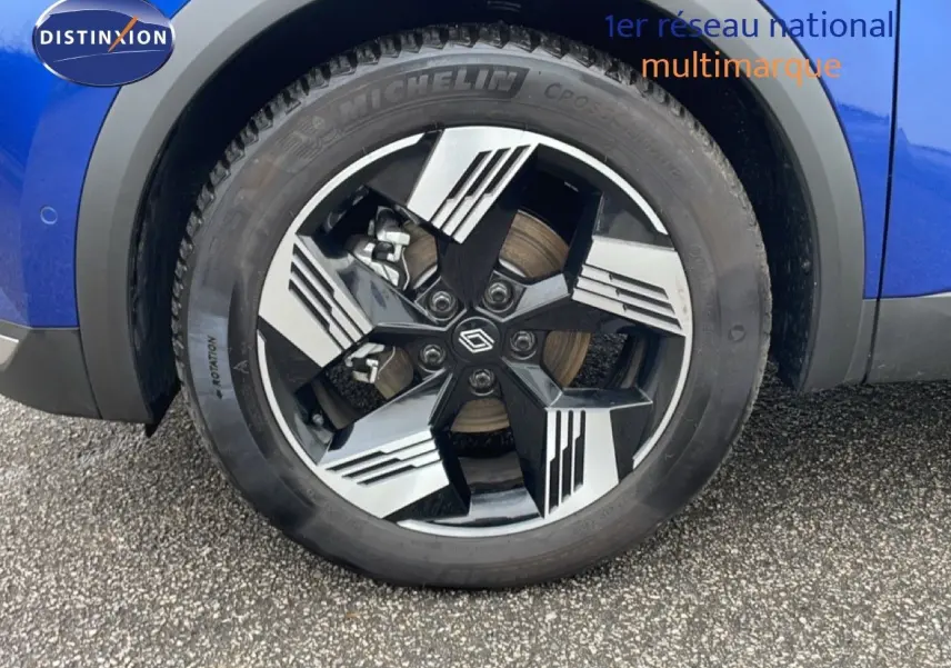 Gros plan sur la roue avant gauche bleu iron metal de la Renault Symbioz E-Tech Full Hybrid 145ch Iconic avec jante noire et argent.