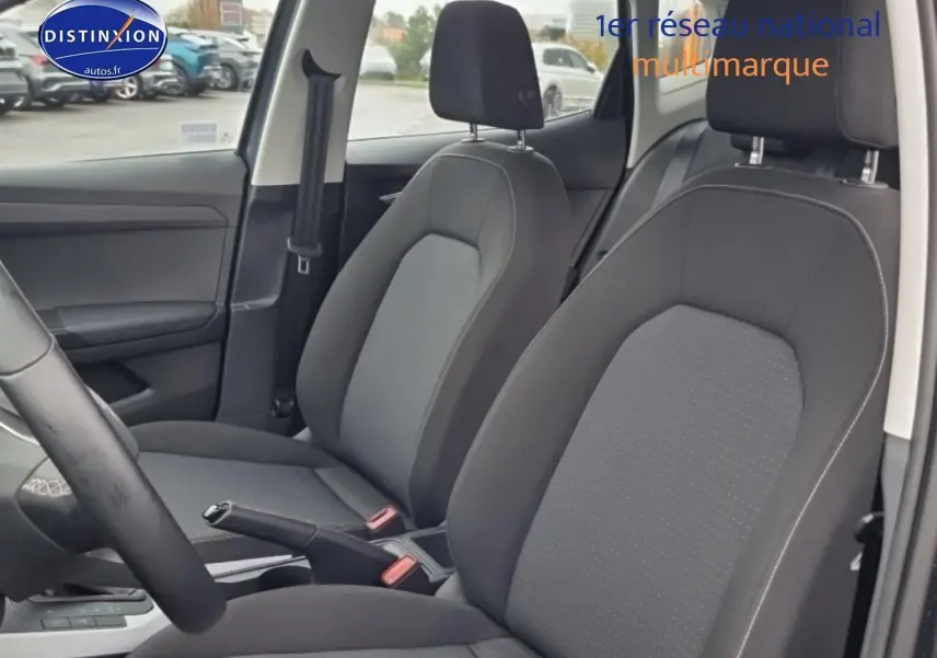 Vue intérieure côté avant droit montrant les sièges tissu gris et le levier de frein à main d'une SEAT Arona 2025.