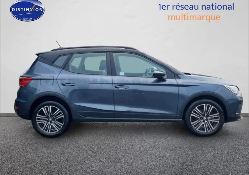 Vue latérale droite d'un SEAT Arona gris magnétique 2025 avec jantes 17 pouces et barres de toit noires.