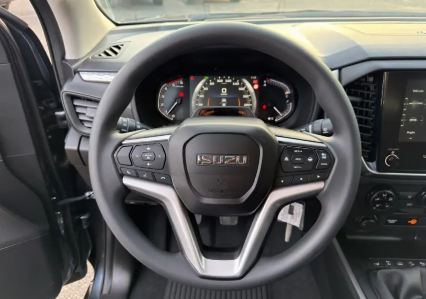 Vue centrée sur le volant multifonctions d’un Isuzu D-MAX 2.2 TD gris avec tableau de bord et écran tactile visibles.