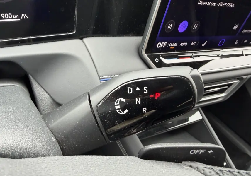 Gros plan sur le levier de vitesses noir brillant du Volkswagen Tiguan 2025, avec tableau de bord et écran tactile en arrière-plan.