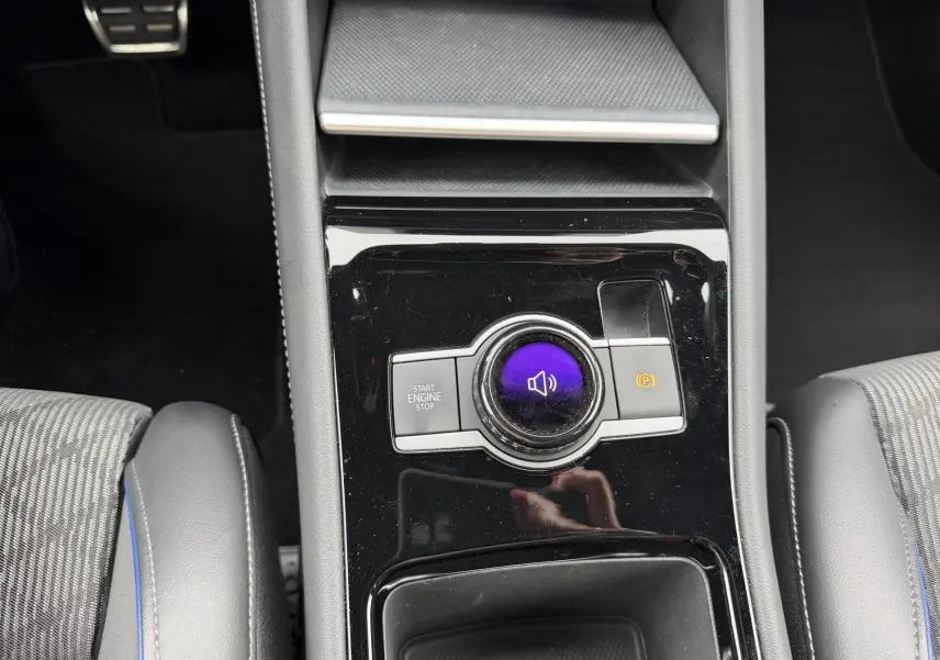 Vue plongeante sur la console centrale noire brillante du Volkswagen Tiguan 2025 avec bouton start/stop et frein à main électronique.