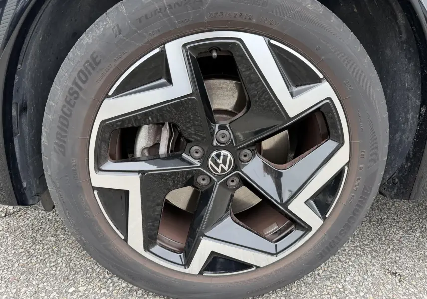 Gros plan sur la jante alliage 19 pouces bicolore noire et argentée du Volkswagen Tiguan gris, avec logo VW central.