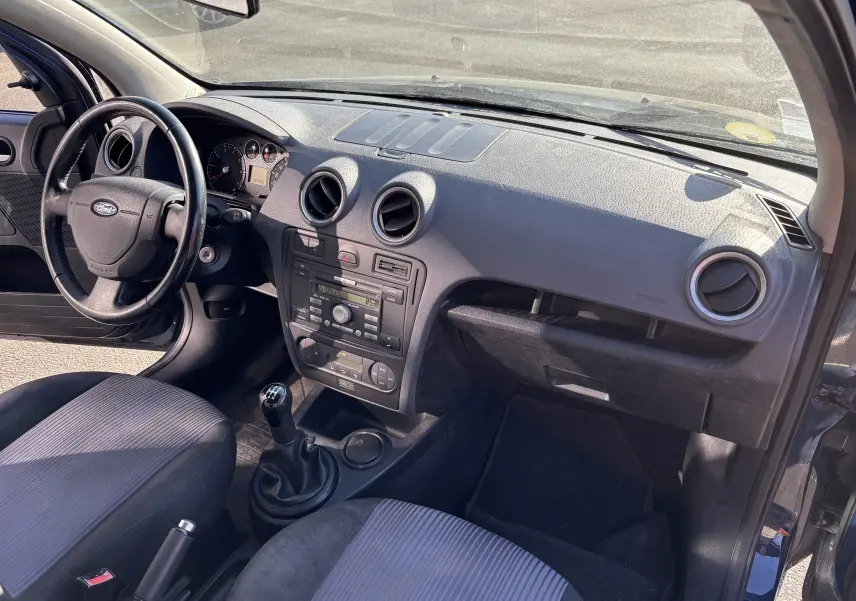 Vue intérieure côté conducteur de la Ford Fusion 2009 avec tableau de bord noir et levier de vitesse manuel.