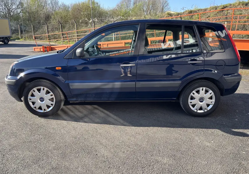 Vue de profil côté gauche d'une Ford Fusion 2009 bleu foncé avec cinq portes et jantes acier.