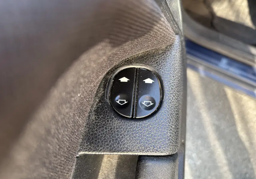 Boutons de commande des vitres électriques sur la porte intérieure côté gauche d'une Ford Fusion bleu 2009.
