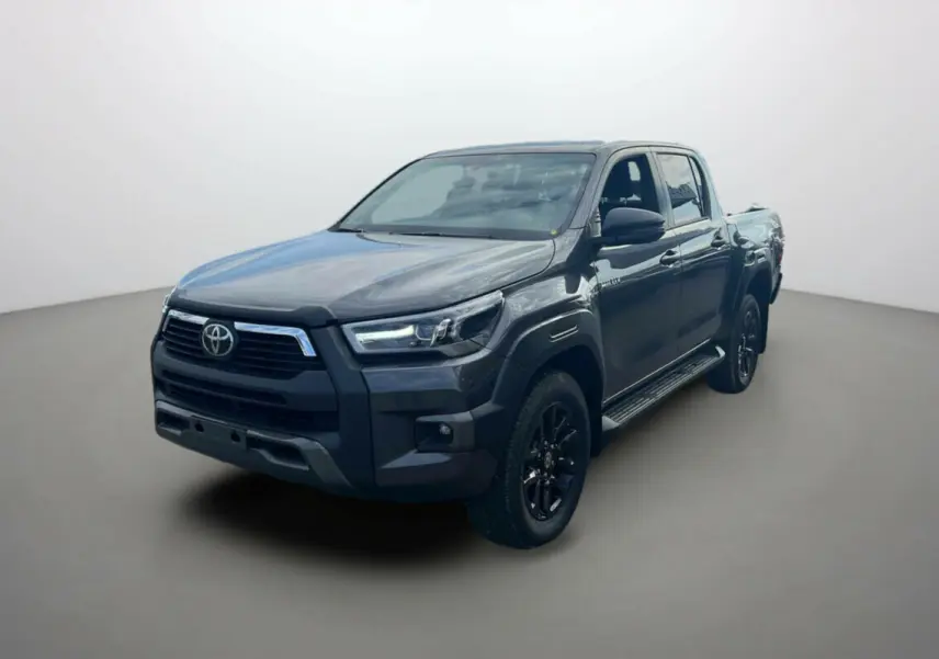 Toyota Hilux 4x4 gris atlas en 3/4 avant droit, avec jantes noires et calandre imposante, modèle 2025 Invincible.