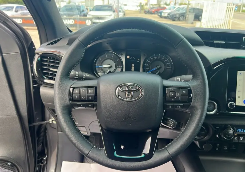 Vue centrée sur le volant du Toyota Hilux 2025 gris atlas, montrant commandes intégrées et tableau de bord numérique.