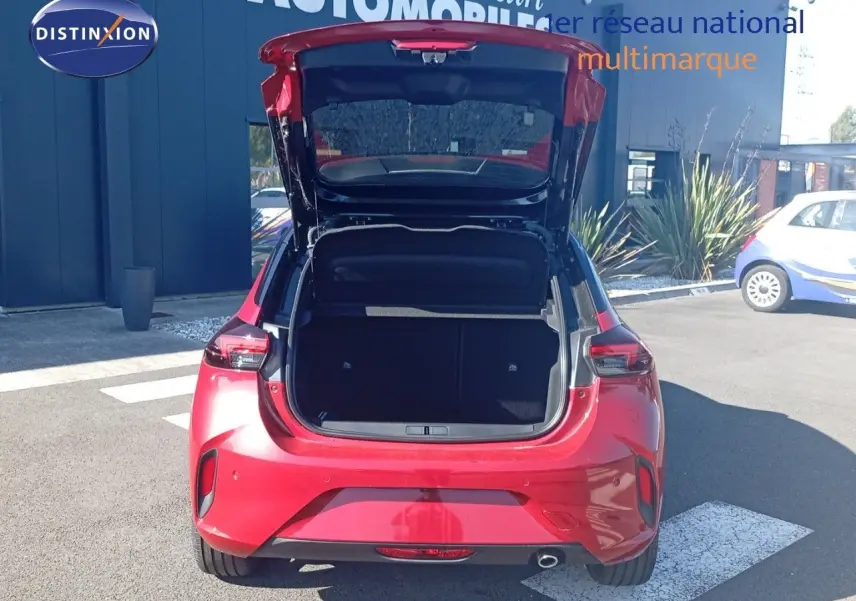 Opel Corsa 2023 rouge métal avec toit noir vue arrière, coffre ouvert montrant l'espace de chargement.