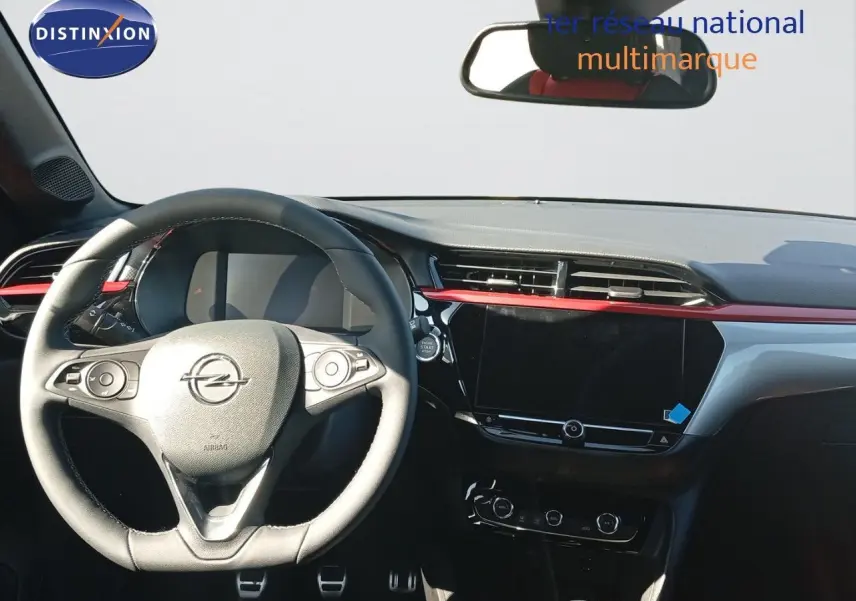 Intérieur Opel Corsa 2023 vu de face, tableau de bord noir avec bande rouge et volant cuir multifonctions.