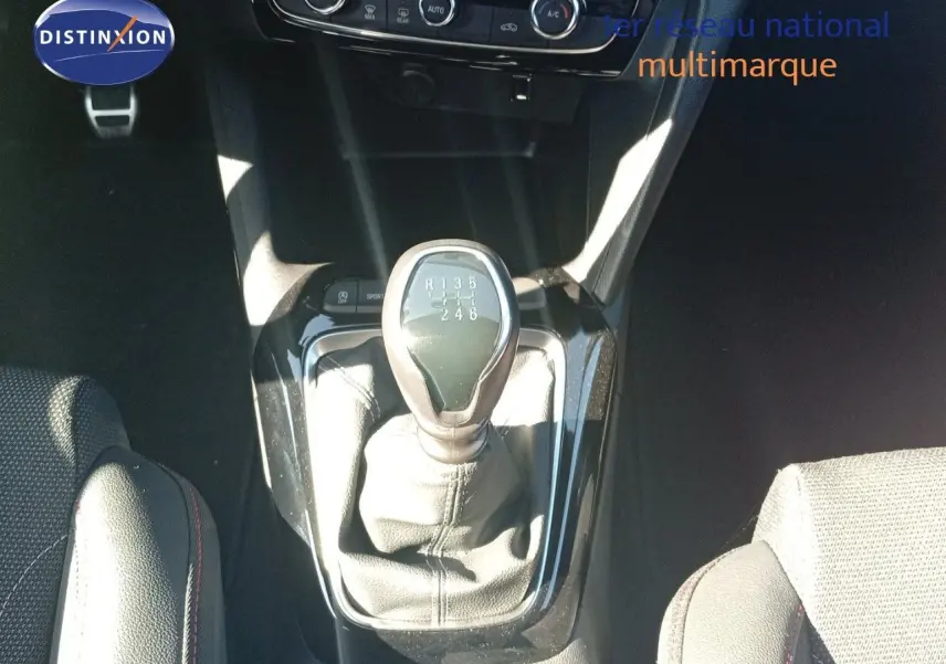 Le levier de vitesses manuel 6 rapports de l'Opel Corsa 1.2 Turbo 2023, entouré de sièges tissu noir.