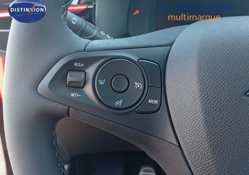 Gros plan sur les commandes de régulateur de vitesse au volant d'une Opel Corsa rouge métal 2023.