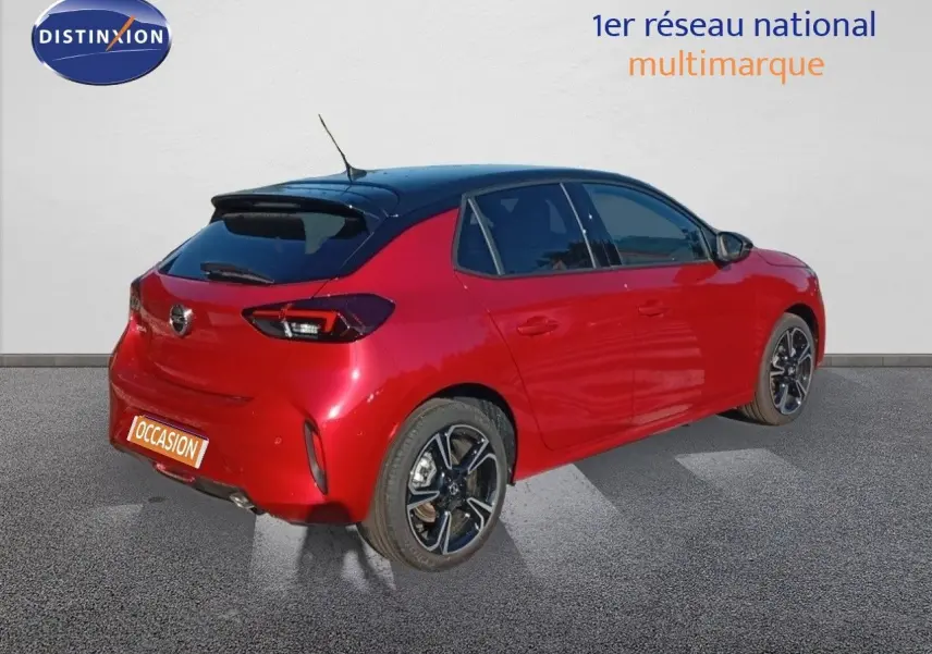 Opel Corsa 1.2 Turbo 2023 rouge métal avec toit noir, vue 3/4 arrière droit, jantes alliage noires et rouges.