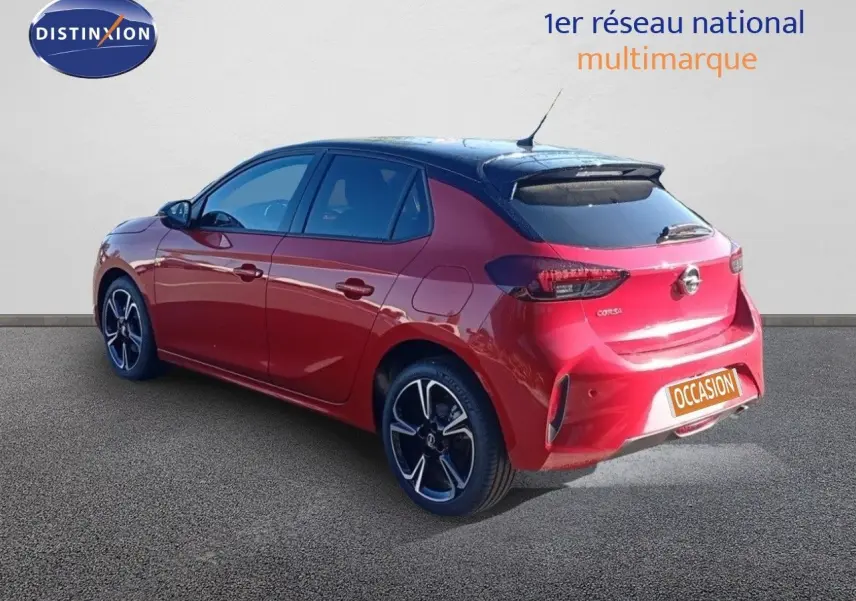 Opel Corsa rouge métal avec toit noir vue 3/4 arrière droit, jantes noires et feux arrière LED.
