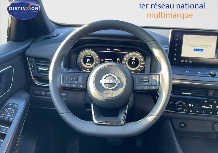 Vue frontale de l'intérieur du Nissan Qashqai blanc nacré, volant cuir noir et tableau de bord digital avec écran tactile.