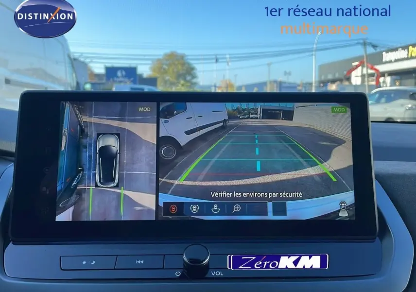 Affichage écran caméra 360° du Nissan Qashqai blanc nacré toit noir, vue arrière avec marquages au sol visibles.