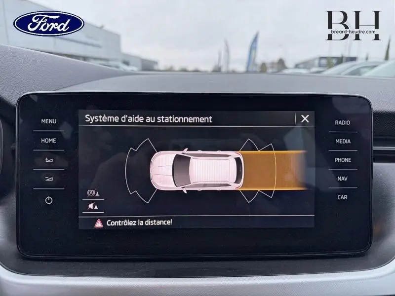 Écran tactile montrant le système d'aide au stationnement d'une Skoda Kamiq gris Météore vue de dessus