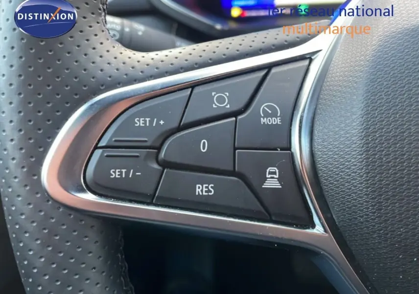 Gros plan sur les commandes de régulateur de vitesse au volant en cuir perforé noir du Renault Symbioz gris cassiopée métal.