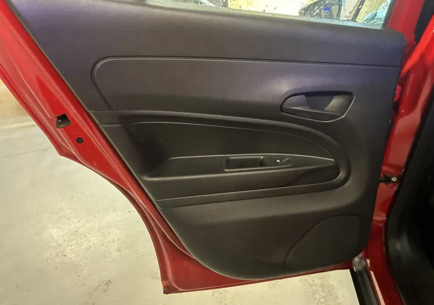 Vue intérieure de la porte arrière droite noire sur FIAT 600 rouge 2024, avec poignée et commande de fenêtre visible.