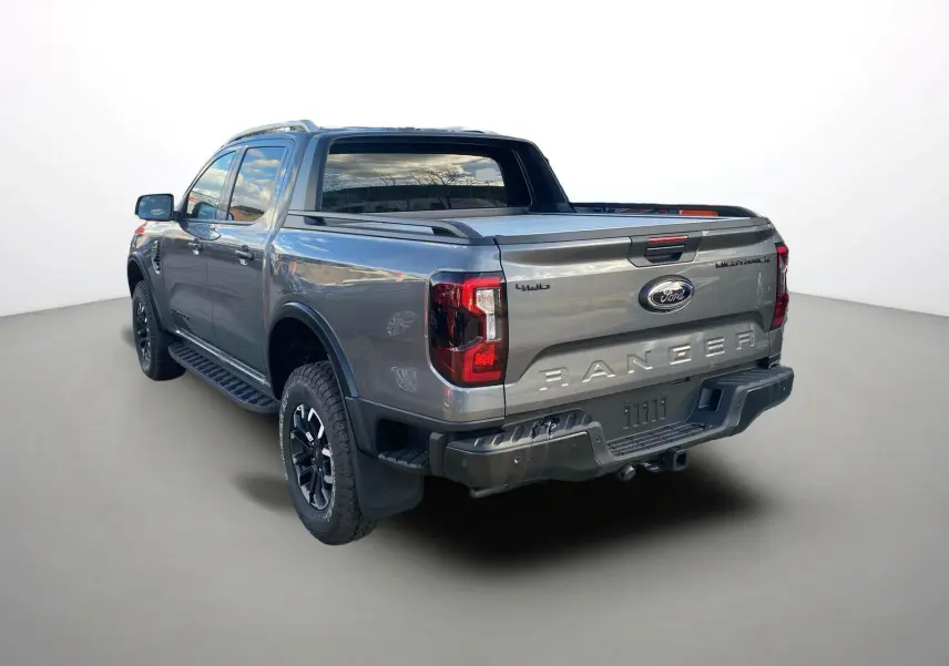 Vue 3/4 arrière du Ford Ranger gris carbone 2025 avec ridelle coulissante et jantes noires distinctives.