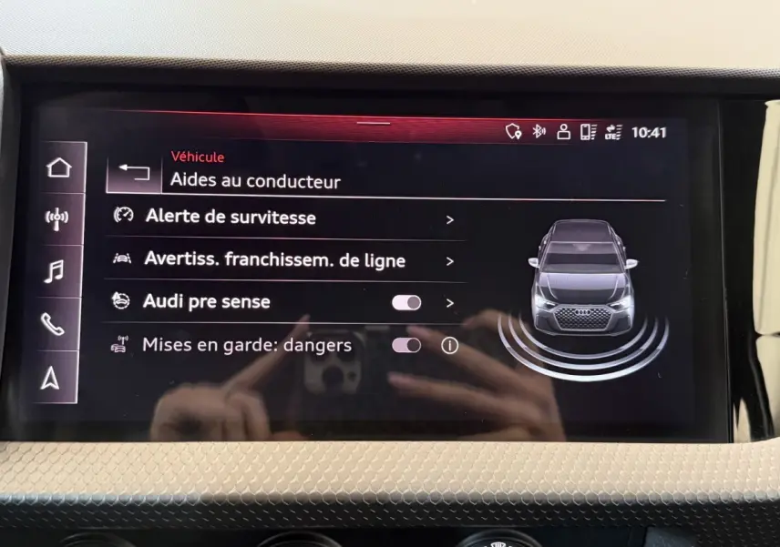 Écran tactile central de l'Audi A1 noir montrant les aides au conducteur avec vue avant du véhicule stylisée.