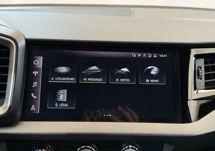Écran tactile central de l’Audi A1 2021 affichant les menus messages, météo, news et utilisateurs, intérieur noir.
