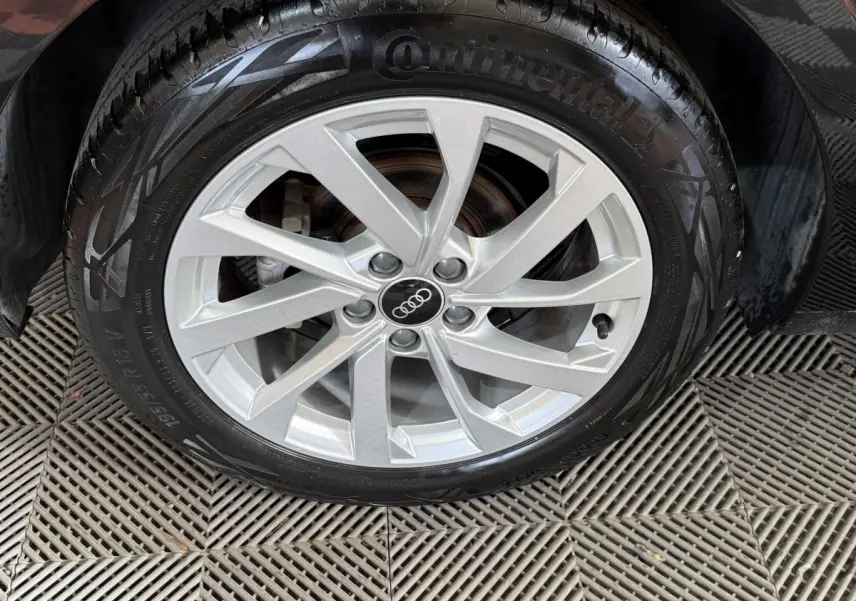 Gros plan sur la roue avant droite avec jante argentée et pneu Continental d'une Audi A1 noire.