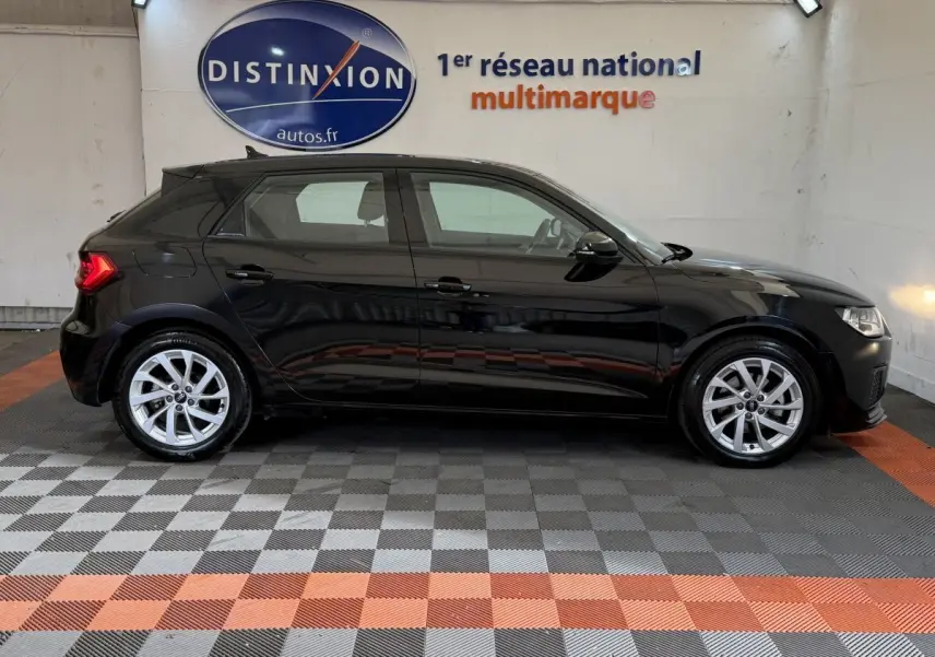 Audi A1 Business Line noire vue de profil côté gauche, avec jantes argentées et feux arrière allumés.