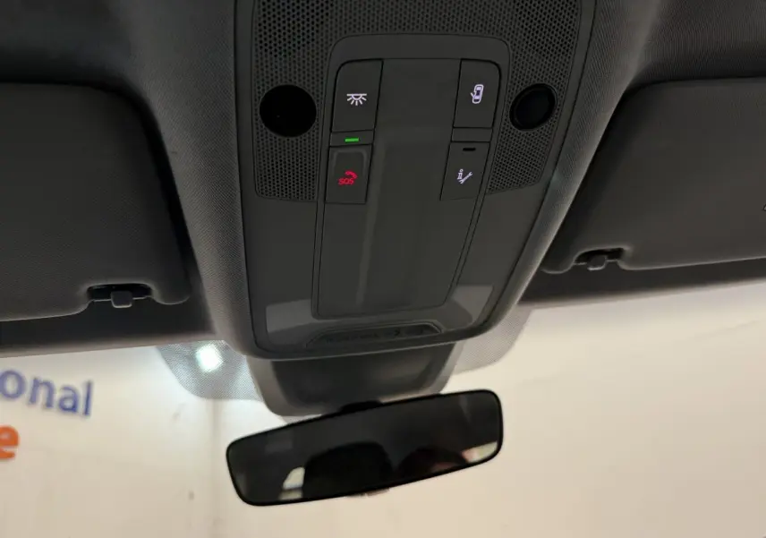 Vue intérieure du plafonnier avec boutons SOS et éclairage, miroir intérieur et pare-soleil gris d'une Audi A1 noire.