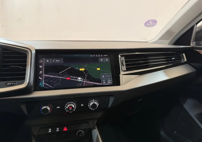 Tableau de bord de l'Audi A1 noir, vue de face sur l'écran tactile de navigation et les commandes de climatisation.