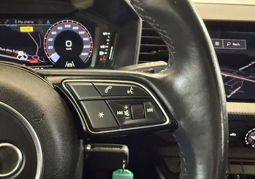 Gros plan sur le volant cuir noir multifonctions de l'Audi A1 2021 avec affichage numérique et navigation visible.