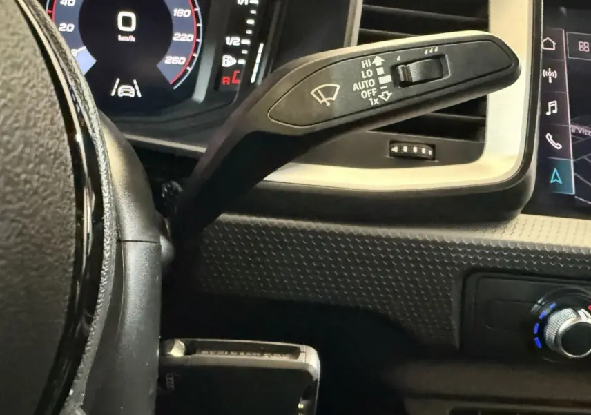 Gros plan sur le commodo d’essuie-glace à gauche du volant cuir noir de l’Audi A1 2021, avec tableau de bord numérique.