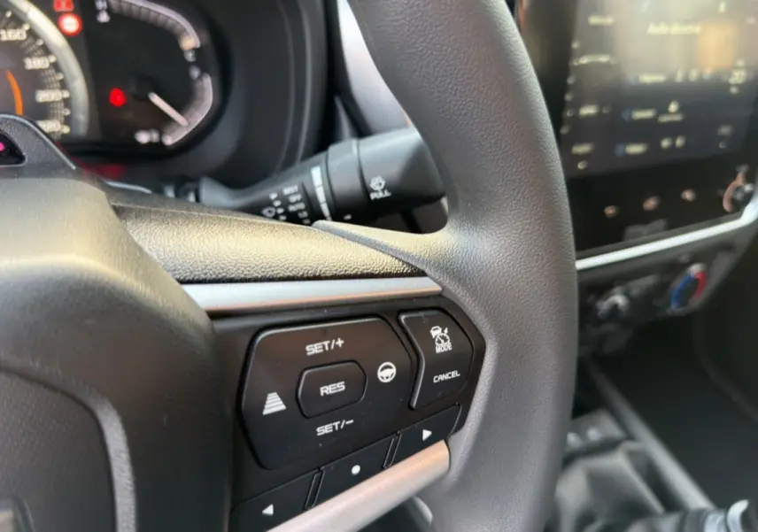 Gros plan sur le volant multifonctions de l'Isuzu D-MAX 2026 avec commandes de régulateur et écran tactile flou en arrière-plan.