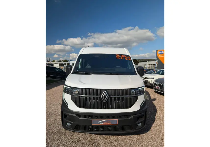 Vue frontale d'un Renault Master blanc avec calandre noire et logo Renault bien visible sous un ciel bleu.