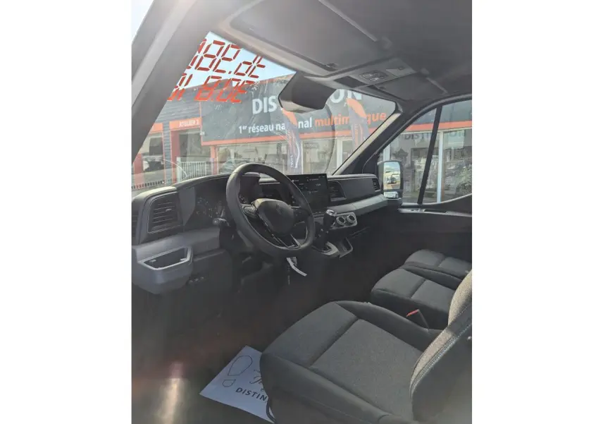 Intérieur du Renault Master 2025 vu côté conducteur, sièges gris chiné avec surpiqûres bleues et tableau de bord moderne.